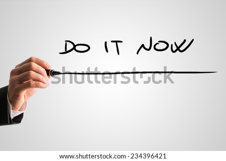 Man writing business inspiration message Do it now on a virtual screen or interface with a black marker over a light grey background with copyspace.