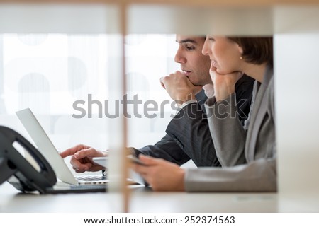 Business partners  Discussing Business Matters While Looking at Laptop Computer on the Table.