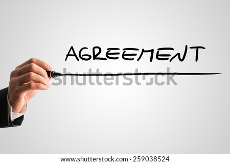 Closeup of hand of a mediator writing the word Agreement from behind a virtual screen or interface on a light grey background.