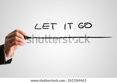 Man writing the words - Let it go - with a black marker pen from behind a virtual screen or interface on a light grey background with copyspace, close up view of the text and his hand.