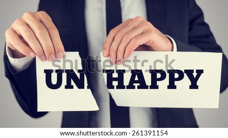 Close up Conceptual Businessman Tearing a White Paper with Unhappy - Happy Message Isolated on a Gray Background, Toned Retro Effect.