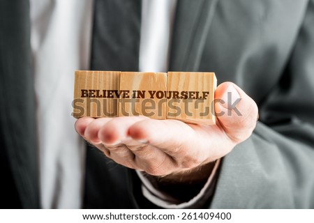 Close up Conceptual Businessman Showing Wooden Blocks with Believe in Yourself Message in Front of the Camera.