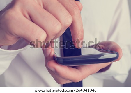 Conceptual Businessman Busy Clicking his Mobile Phone Screen with his Bare Finger, Captured in Close up, Toned Retro Effect.