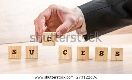 Close up Hand of a Businessman Arranging Small Wooden Blocks on the Table for Success Concept.