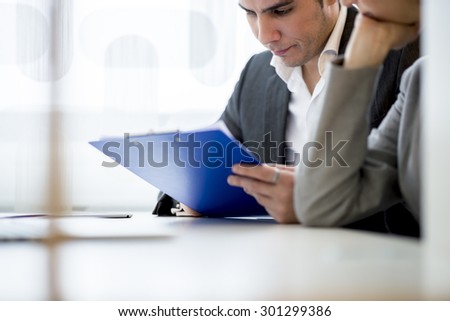 Young business executives, a business man and woman, sitting in an office checking an application or document preparing for interview with a probable new employee.
