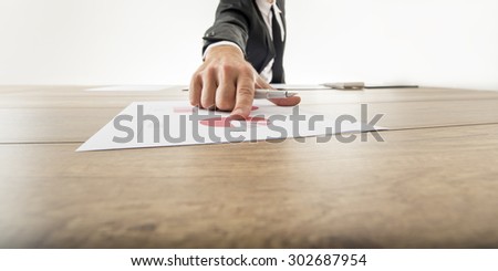 Low angle wide angle view with receding perspective of a businessman pointing to an analytical pie graph on a wooden desk with his finger.