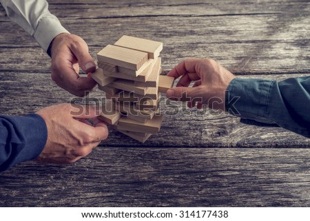 Three Businessmen Hands Playing Wooden Tower Game on Top of a Rustic Wooden Table. Conceptual of Teamwork, Strategy and Vision.