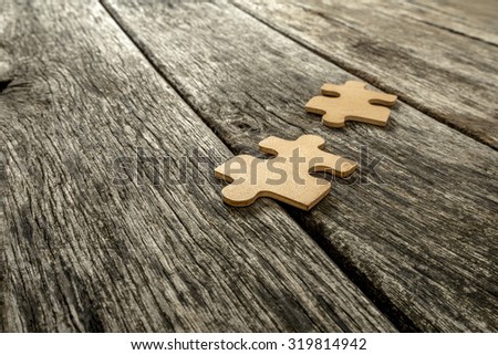 Two puzzle pieces lying on wooden rustic boards. Conceptual of innovation, solution finding and integration.