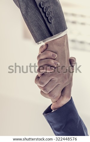 Retro image of business partners - man and woman shaking hands to close a deal, in agreement, greeting or congratulations, view from underneath their hands.