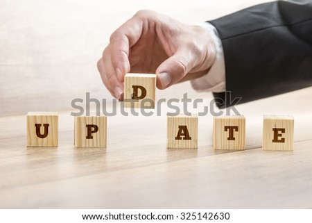 Business or education concept of updating a system, offer or personal knowledge and abilities  - male hand arranging wooden cubes with letters to read Update.