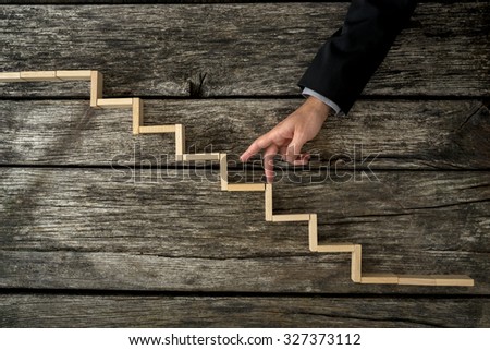 Businessman or student walking his fingers up wooden steps resembling a staircase mounted in rustic wooden boards in a conceptual image of personal and career development, success and aspiration.