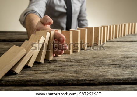 Man stopping domino effect on wooden table. Business success concept. Copy space.