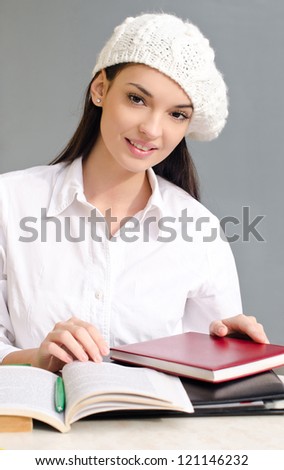 Beautiful brunette student girl learning. Dressed in white wearing a beret.