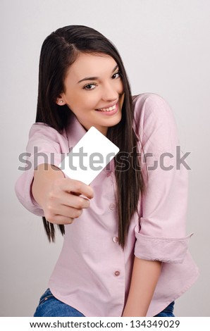 Young woman smiling holding a business card. Beautiful girl offering you a visit card.
