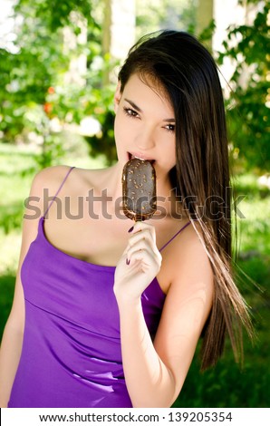 Beautiful woman eating a delicious ice cream. Girl relaxing in the park on a hot summer day enjoying a delicious chocolate ice cream.