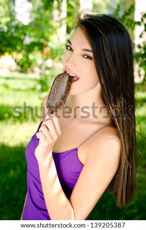 Beautiful woman eating a delicious ice cream. Girl relaxing in the park on a hot summer day enjoying a delicious chocolate ice cream.