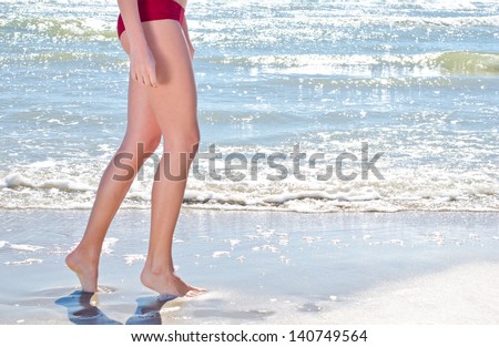 Walking on the beach. Close up on legs walking along the sea side.