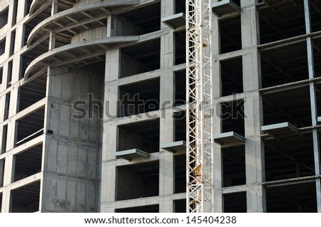 Empty building under construction. Construction stopped due to crisis. Abandoned block of flats and a rusty crane.