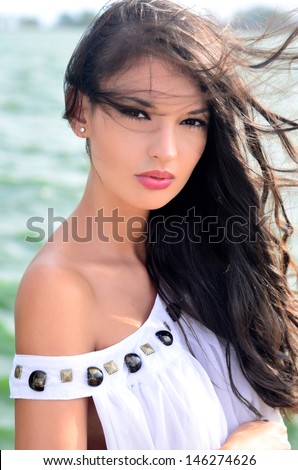 Sexy girl with hair in the wind. Beautiful girl in white dress, wind blowing her hair, outdoors, near the water.