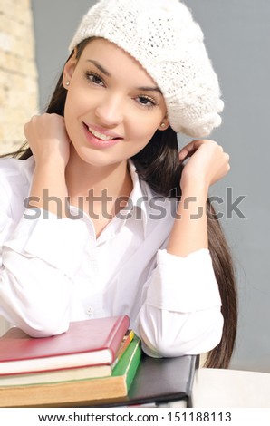 Beautiful student girl with books. Beautiful brunette student girl learning. Dressed in white wearing a beret.