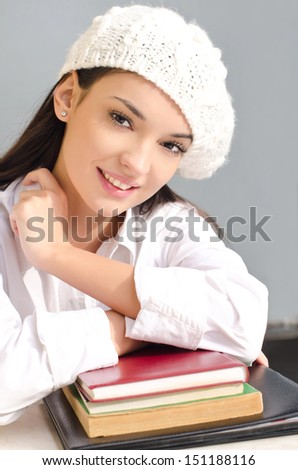Beautiful student girl with books. Beautiful brunette student girl learning. Dressed in white wearing a beret.
