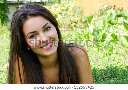 Girl smiling lying on the grass. Portrait of a beautiful woman relaxing in the garden on a hot summer day.