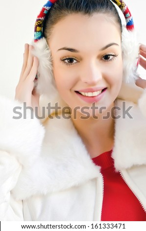 Attractive girl with beautiful smile, wearing ear muffs. Woman dressed for winter season.