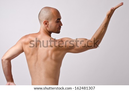 Topless dancer, man stripper posing with his back and arm up. Fit bodybuilder.