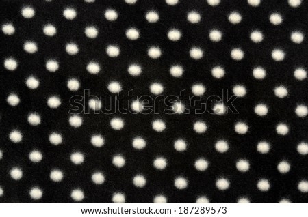 Polka dots background. Closeup on black with white dots wool texture.