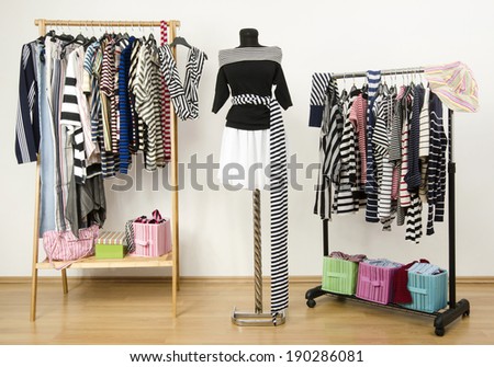 Dressing closet with striped clothes arranged on hangers. Black and white outfit on a mannequin. Colorful wardrobe full of clothes and accessories with stripes pattern.