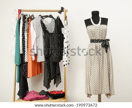 Dressing closet with polka dots clothes arranged on hangers and a dress on a mannequin. Colorful wardrobe with polka dots clothes and accessories.