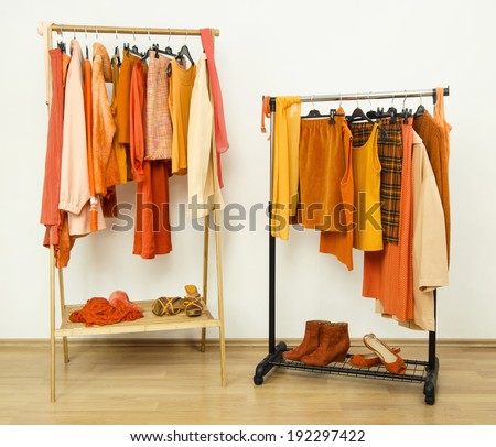 Dressing closet with orange clothes arranged on hangers. Wardrobe full of all shades of orange clothes, shoes and accessories.