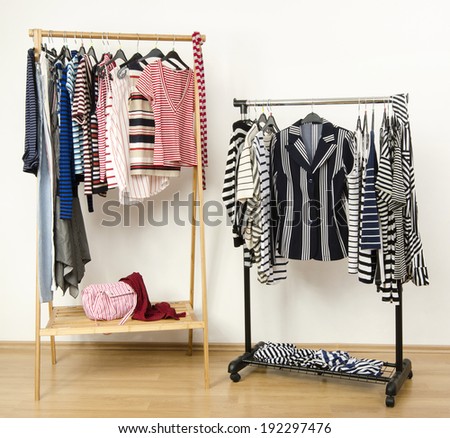 Dressing closet with striped clothes arranged on hangers. Colorful wardrobe full of clothes and accessories with stripes pattern.