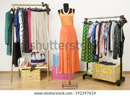 Dressing closet with polka dots clothes arranged on hangers and an orange outfit on a mannequin. Colorful wardrobe with polka dots clothes and accessories.