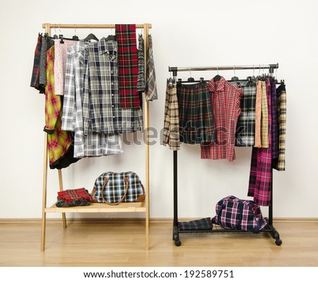 Dressing closet with plaid clothes arranged on hangers on racks. Colorful wardrobe with tartan clothes and accessories.