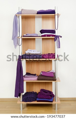 Purple clothes nicely arranged on a shelf. Tidy wardrobe with color coordinated clothes and accessories.