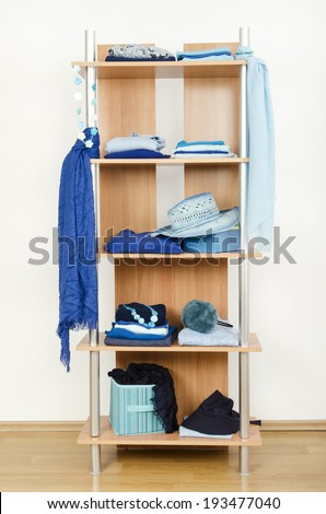Blue clothes nicely arranged on a shelf. Tidy wardrobe with color coordinated clothes and accessories.