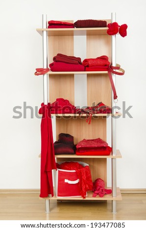 Red clothes nicely arranged on a shelf. Tidy wardrobe with color coordinated clothes and accessories.