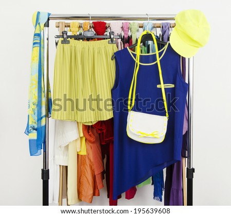 Cute neon green and blue outfit displayed on a rack. Wardrobe with colorful summer clothes and accessories.