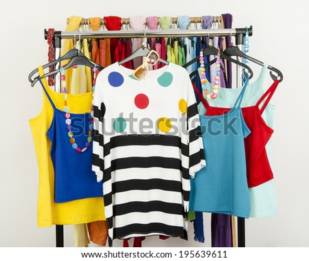 Cute summer outfits displayed on a rack. Wardrobe with colorful summer clothes and accessories.