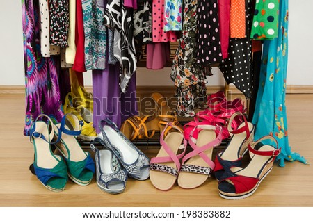 Close up on summer sandals in a wardrobe. Dressing closet with colorful clothes and shoes nicely arranged.