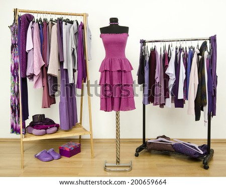 Wardrobe with purple clothes arranged on hangers and a dress on a mannequin. Dressing closet with all shades of violet clothes, shoes and accessories.