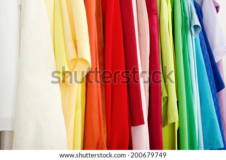 Close up on color coordinated clothes on hangers in a store. Detail on all colors clothes hanging on a rack nicely arranged.