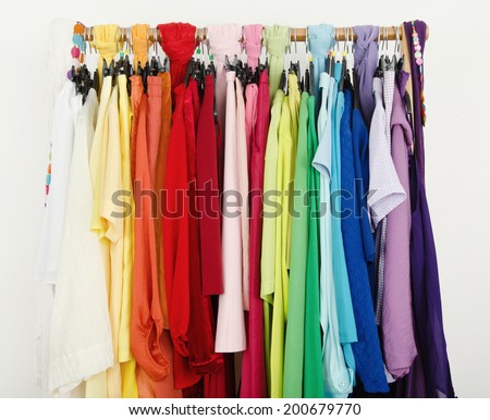 Close up on color coordinated clothes on hangers in a store. All colors clothes hanging on a rack nicely arranged.