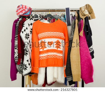 Cute sweaters displayed on a rack. Wardrobe with colorful winter clothes and accessories.