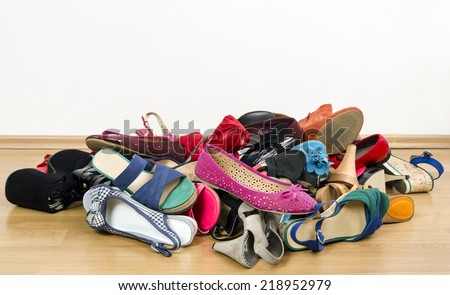 Big pile of colorful woman shoes. Untidy stack of shoes thrown on the ground.
