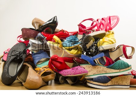 Close up on big pile of colorful woman shoes. Untidy stack of shoes thrown on the ground.