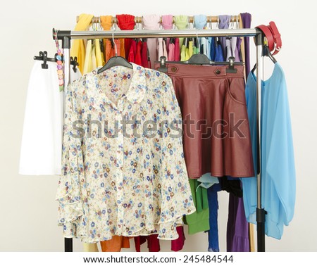 Cute floral outfits displayed on a rack. Wardrobe with colorful summer clothes and accessories.