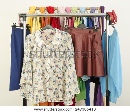 Cute floral outfits displayed on a rack. Wardrobe with colorful summer clothes and accessories.