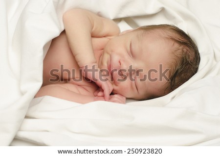New born baby boy smiling in his sleep. Small baby happy laughing during his nap.